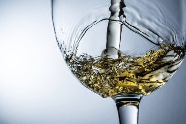 Gri arka plan, beyaz şarap bir bardak dökülen dere üzerinde beyaz şarap sıçrama.