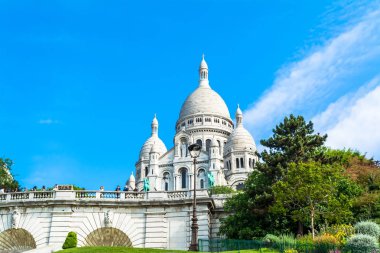 Sacre Coeur Bazilikası'na gün mavi parlak gökyüzü ve yeşil çim ve çiçek açan ağaçlar ile Paris'te.