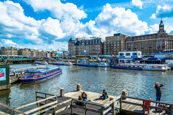 Amsterdam, Niederlande - 28. Mai 2015: Ufer des Kanals in amsterdam mit Touristenbooten an einem sonnigen Tag mit Kumuluswolken und blauem Himmel. amsterdam ist als Venedig des Nordens bekannt, es hat 1.200 Brücken und 165 Kanäle. — Stockfoto