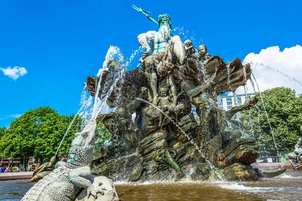Neptunbrunnen in Berlin Nahaufnahme an sonnigem Tag mit blauem Himmel und grün blühenden Bäumen. — Stockfoto