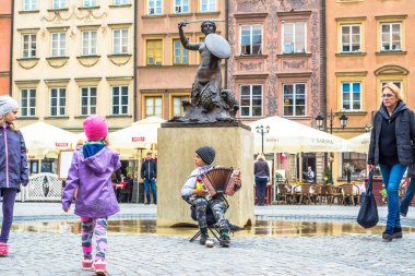 Varşova, Polonya 07 Mayıs 2017: Çocuk sokak müzisyeni Varşova eski şehir denizkızı heykeli yakın çevresinde çalıştırın. Deniz kızı Varşova bir sembolüdür. Polonyalılar bir sirenka ara.