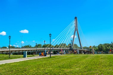 Varşova, Polonya 16 Temmuz 2017: Modern köprü Varşova. Turistler Köprüsü yakınlarında bir denizkızı heykeli yakın yürüyün. Mavi bir gökyüzü ve yeşil ağaçları ile güneşli yaz günü. Yatay fotoğraf.