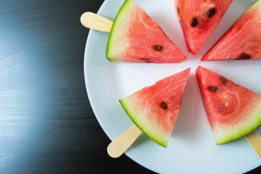 bir sopa dondurma yakın siyah bir zemin üzerine beyaz plaka üzerinde çekim üzerinden dilim karpuz kesmek