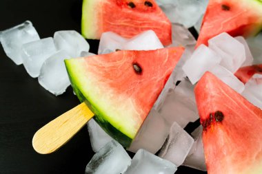 Dondurmanın içine buz küp yakın çekim bir siyah arka plan üzerine bir sopa dilim karpuz kestim