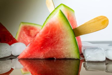 Dondurmanın içine buz küp yakın çekim yansıma koyu arka plan üzerinde ile bir sopa dilim karpuz kestim