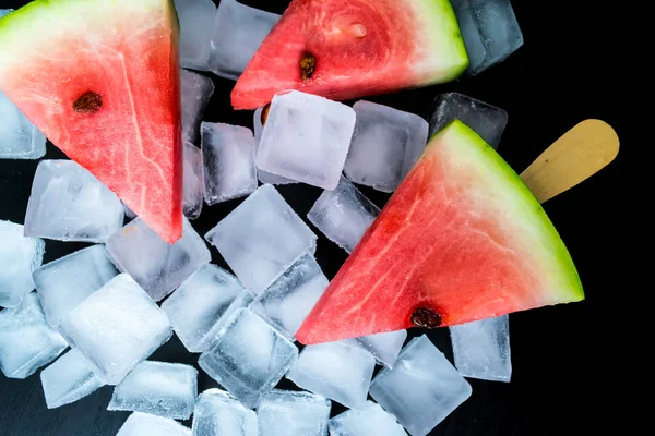 Dondurmanın içine buz küp yakın çekim bir siyah arka plan üzerine bir sopa dilim karpuz kestim