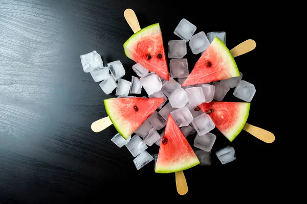 Dondurmanın içine buz küp yakın çekim bir siyah arka plan üzerine bir sopa dilim karpuz kestim