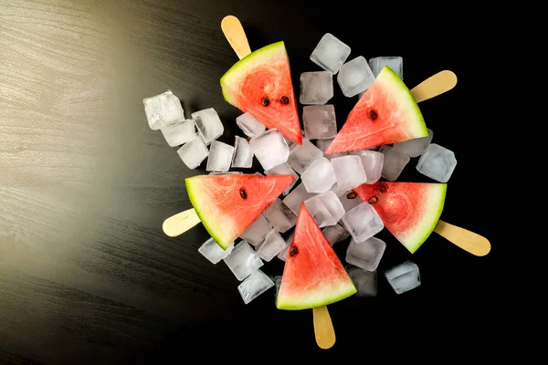 Dondurmanın içine buz küp yakın çekim bir siyah arka plan üzerine bir sopa dilim karpuz kestim