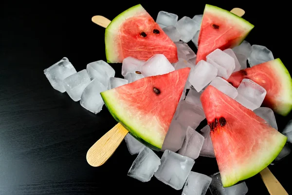 Wassermelone geschnitten Scheibe auf einem Stock aus Eis in Eiswürfel Nahaufnahme auf schwarzem Hintergrund — Stockfoto