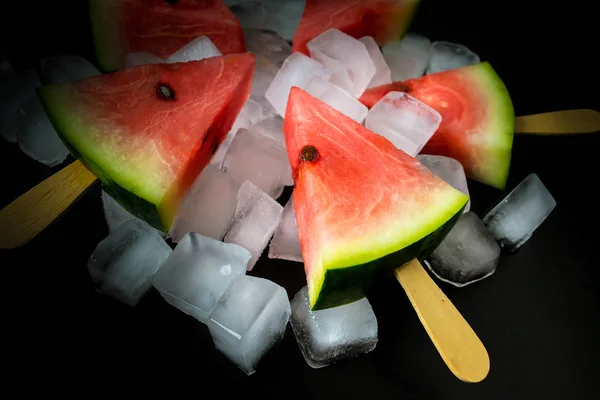 Tranche de pastèque coupée sur un bâton de crème glacée en cube de glace gros plan sur un fond noir — Photo