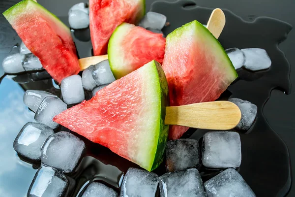 Dondurmanın içine buz küp yakın çekim bir siyah arka plan üzerine bir sopa dilim karpuz kestim