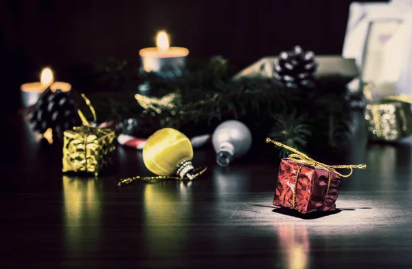 Neujahrsgeschenke auf einem Holztisch mit Kerzen und einem Weihnachtsbaum mit Zapfen. vintage, Grunge alten Retro-Stil. — Stockfoto