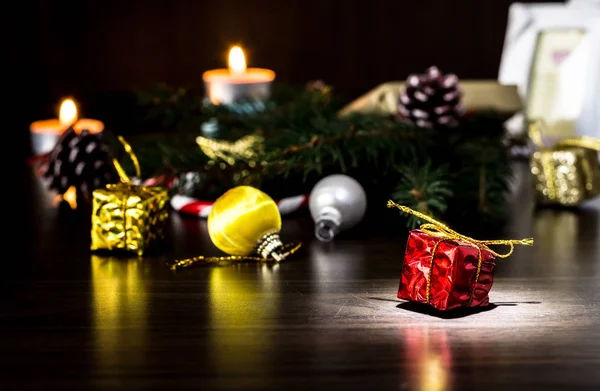 Os presentes de Ano Novo em uma mesa de madeira com velas e uma árvore de Natal com cones . — Fotografia de Stock