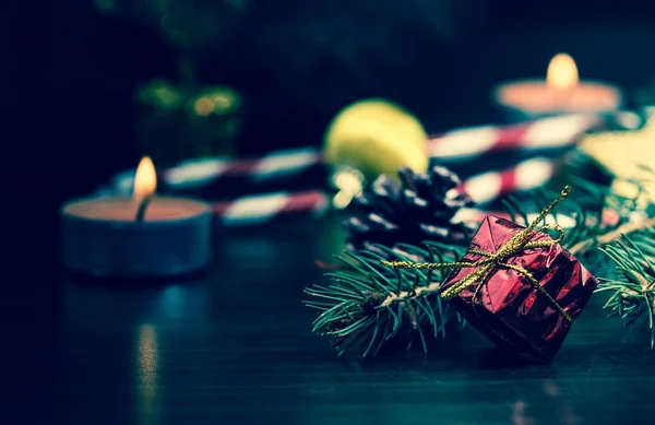 Presente de Ano Novo em embalagem vermelha com um arco de ouro perto da pata da árvore de Natal macro close-up em uma mesa de madeira. Vintage, grunge velho estilo retro . — Fotografia de Stock