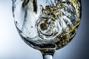 Beyaz şarap sıçrama yakın çekim makro gri arka plan, beyaz şarap bir bardak dökme akışı üzerinde.