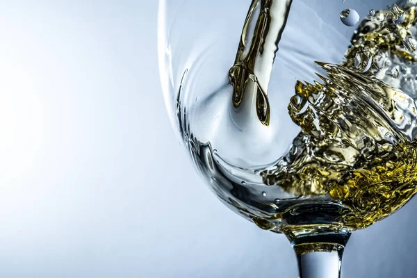 Vitt vin splash närbild makro på grå bakgrund, ström av vitt vin hälla i ett glas. — Stockfoto