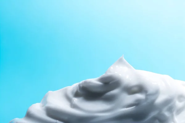 Creme cosmético branco close-up macro textura em fundo azul — Fotografia de Stock