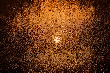 Sisli pencere ışığında bir sokak lambası yakın çekim makro soyutlama arka plan üzerinde Su damlacıkları. Aracın Far ışıktan sisli bir pencerede su damlaları.