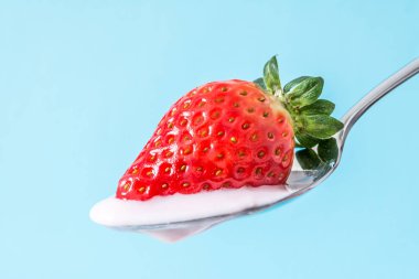 Üzerine bir kaşık çilek Çilek pembe yoğurt krem yakın çekim mavi arka plan ile