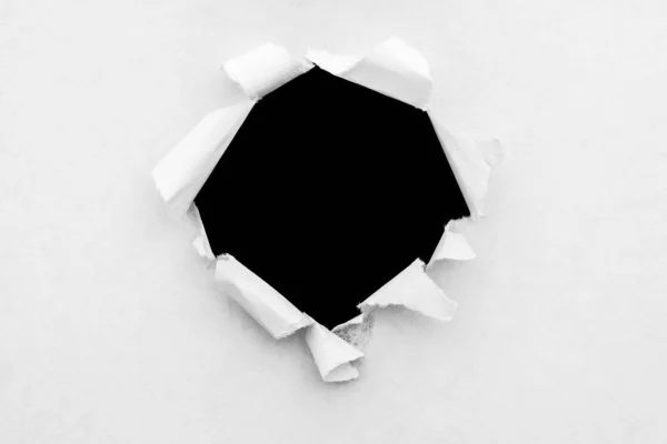 Кругла діра в білому папері з рваними краями та чорним ізольованим фоном всередині . — стокове фото
