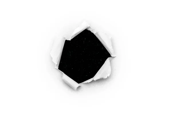 Een rond gat in wit papier met gescheurde randen geïsoleerd close-up met een zwarte achtergrond binnenin met kleurrijke ruimtesterren in het universum. Een gat in papier met uitzicht op de kosmos van het universum. — Stockfoto
