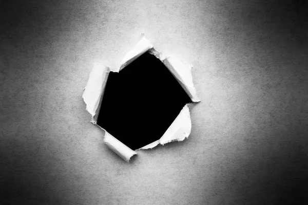 Un agujero en papel vintage con bordes rotos de cerca con un fondo negro aislado en el interior . — Foto de Stock