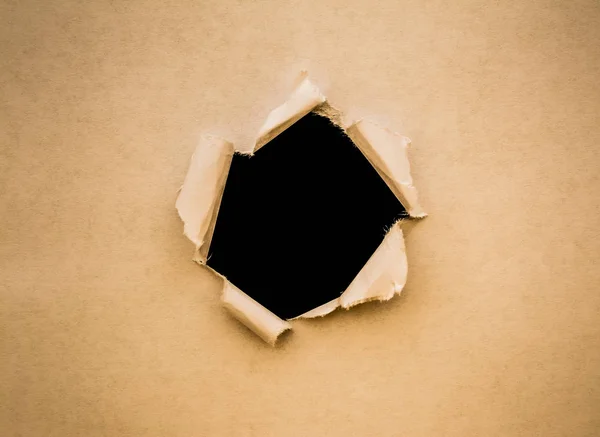 Un agujero en papel vintage con bordes rotos de cerca con un fondo negro aislado en el interior . —  Fotos de Stock