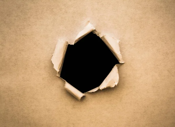 Un agujero en papel vintage con bordes rotos de cerca con un fondo negro aislado en el interior . —  Fotos de Stock