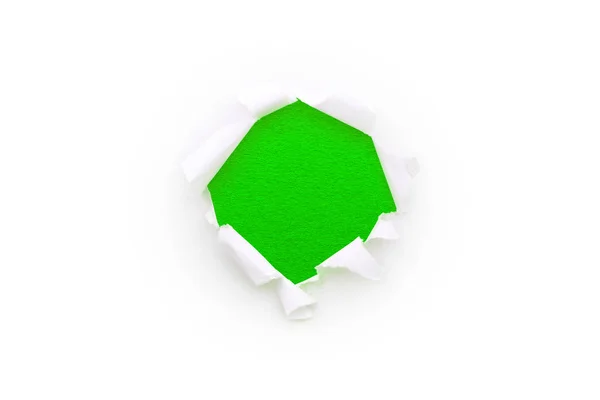 白纸上的一个圆孔，边缘被撕破，与白色背景隔离，里面有明亮的绿色背景。 纸张质地好 — 图库照片