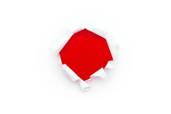A round hole in white paper with torn edges isolated on a white background with a bright red color paper background inside. Good paper texture. — Stock Photo, Image