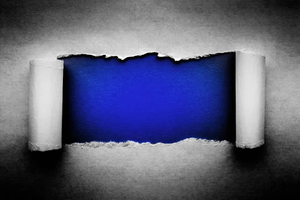 Μια τρύπα σε vintage χαρτί με σκισμένες άκρες γκρο πλαν με σκούρο μπλε φόντο ζωντανό χρώμα στο εσωτερικό. — Φωτογραφία Αρχείου