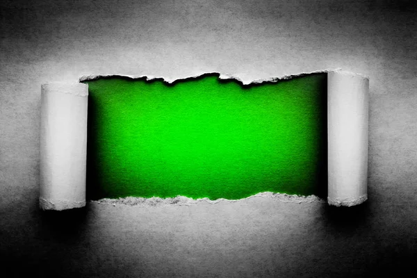 A hole in vintage paper with torn edges close-up with a green vibrant color background inside. — Stock Photo, Image