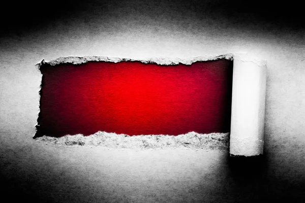 Un agujero en papel vintage con bordes rotos de cerca con un fondo de color rojo vibrante en el interior . —  Fotos de Stock