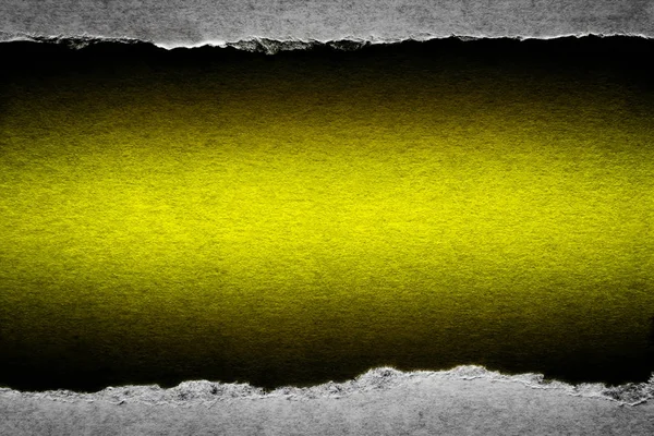 Díra ve vinobraní papíru s roztrženými hranami zblízka se žlutým pulzujícím barevným pozadím uvnitř. — Stock fotografie
