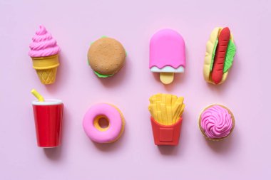 Çeşitli oyuncaklar fast food ve minyatür şekerlemeler. Yumuşak pembe arka planda gölgeler..