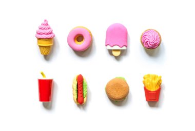 Çeşitli oyuncaklar fast food ve minyatür şekerlemeler. Beyaz arka planda gölgeler var..