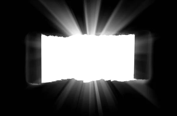 Um buraco em papel preto com bordas rasgadas e luz solar perfurante e raios através dele. Luz solar rompendo a escuridão de um buraco . — Fotografia de Stock
