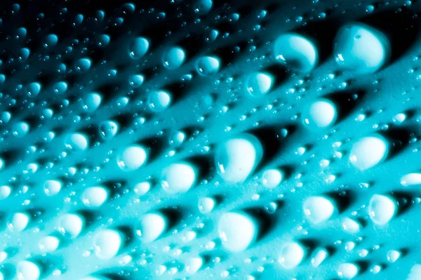 Blauwe druppels water macro op materiaal in zonlicht. — Stockfoto