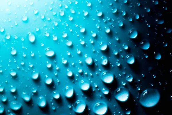 Blauwe druppels water macro op materiaal in zonlicht. — Stockfoto