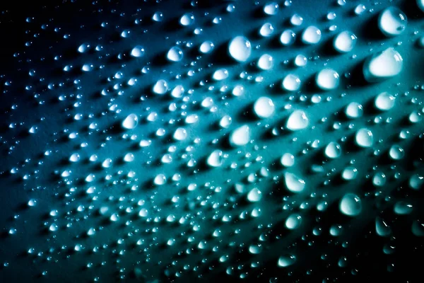 Druppels water met een mooie gladde gradiënt close-up macro op het materiaal in het zonlicht. — Stockfoto