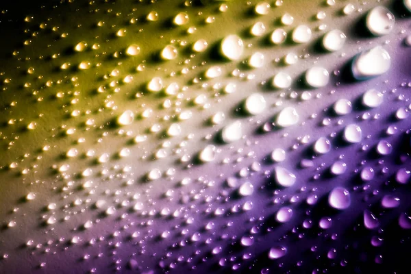 Druppels water met een mooie gladde gradiënt close-up macro op het materiaal in het zonlicht. — Stockfoto