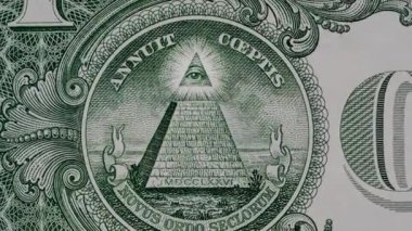 1 Amerikan Doları 'na ait bir makro banknotun piramitli 4k' lik yaratıcı videosu ve üzerinde ışıldayan bir mason gözün etkisi. Piramit, 1 Amerikan Doları 'na yakın çekim..