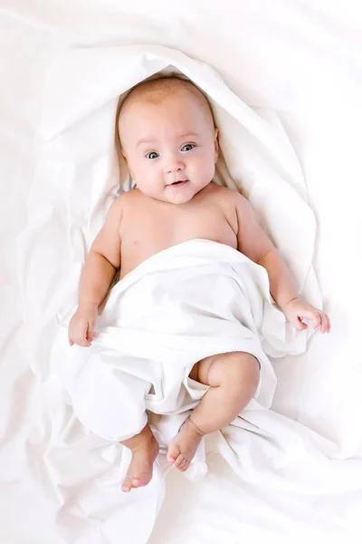El niño recién nacido hermoso yace sobre un fondo blanco —  Fotos de Stock