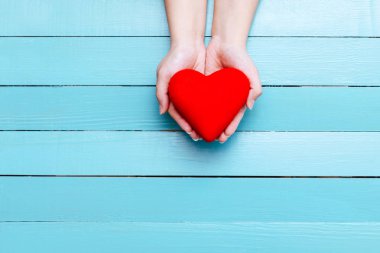 elinde mavi bir arka plan üzerinde kırmızı kalp