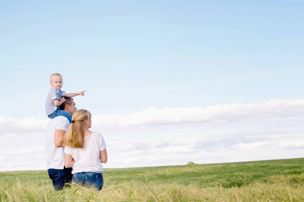 Den lyckliga familjen promenader över fältet — Stockfoto