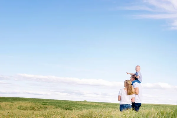 Den lyckliga familjen promenader över fältet — Stockfoto