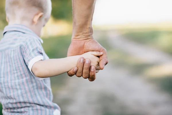 El padre sostiene al hijo por una mano al aire libre — Foto de Stock