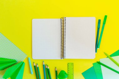 Yaratıcı, moda, minimalist, okul veya office çalışma alanıyla Sarı zemin üzerine yeşil malzemeleri. Düz yatıyordu. Sarı arka plan üstünde Bankası kağıt spiral defter.