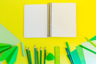 Yaratıcı, moda, minimalist, okul veya office çalışma alanıyla Sarı zemin üzerine yeşil malzemeleri. Düz yatıyordu. Sarı arka plan üstünde Bankası kağıt spiral defter.