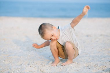 Portre ciddi küçük çocuk içinde belgili tanımlık kum deniz kenarında oynarken okyanus. Olumlu insan duyguları, duygular, joy. Vacations ayırdığınız ve yaz zevk komik şirin çocuk.